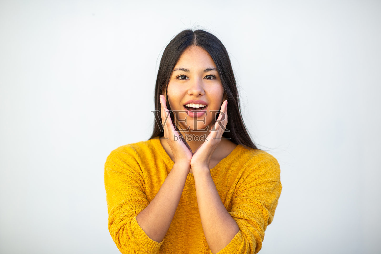 面带微笑的年轻女子双手捂着脸站在白墙边照片摄影图片