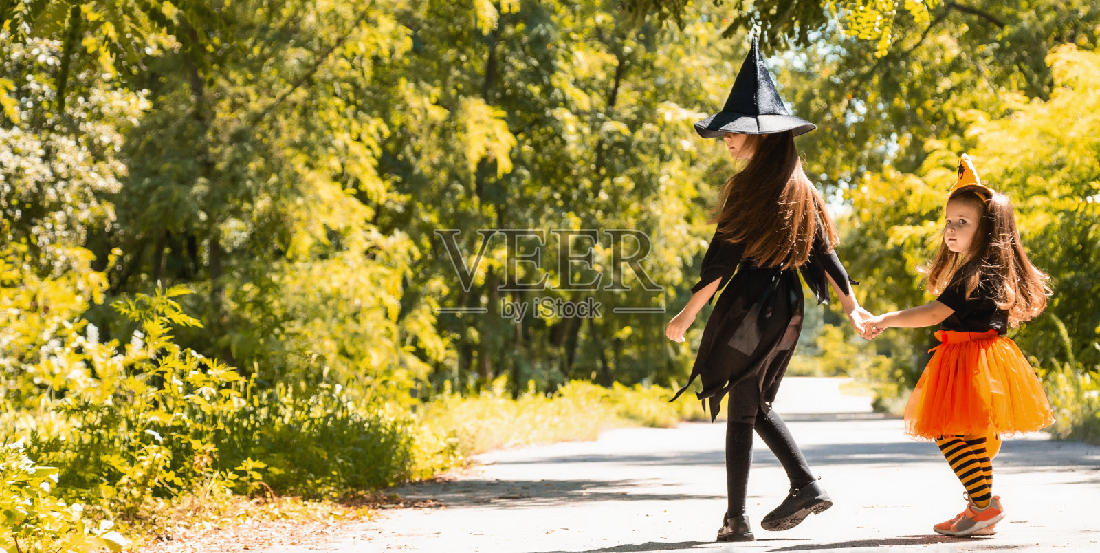 孩子们穿着万圣节服装不给糖就捣蛋。万圣节的庆祝活动。两个跑着的孩子拿着篮子装糖果照片摄影图片