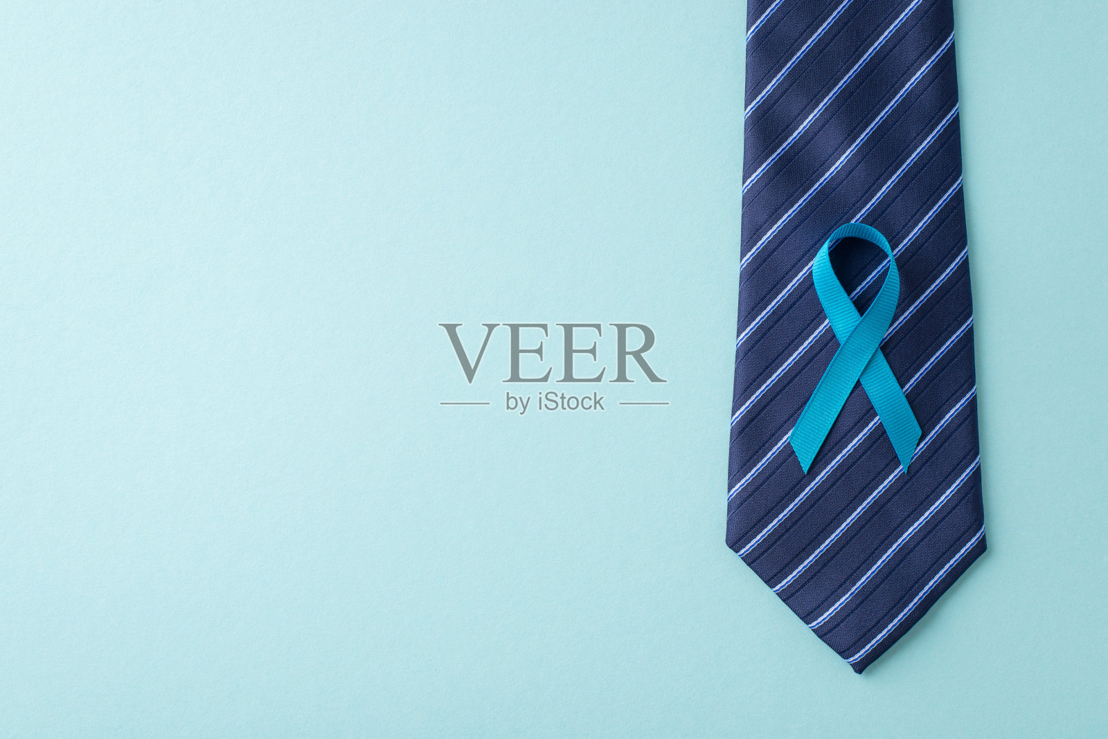 增强男性健康能力。摄护腺癌认知图标的鸟瞰图——蓝色丝带，附在时髦的领带上——在柔和的蓝色背景下，适合文字或广告照片摄影图片