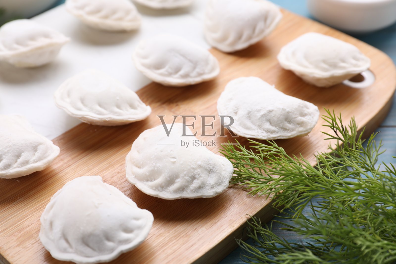 生饺子(varenyky)和食材放在浅蓝色的桌子上，特写照片摄影图片