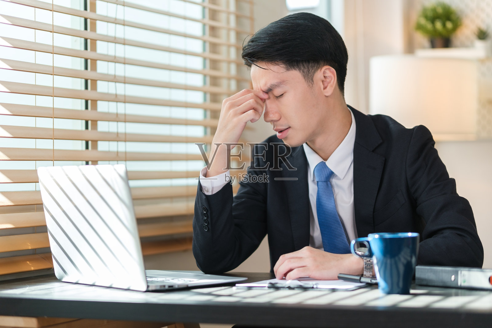 疲惫的商人按摩鼻梁，疲于电脑工作。照片摄影图片