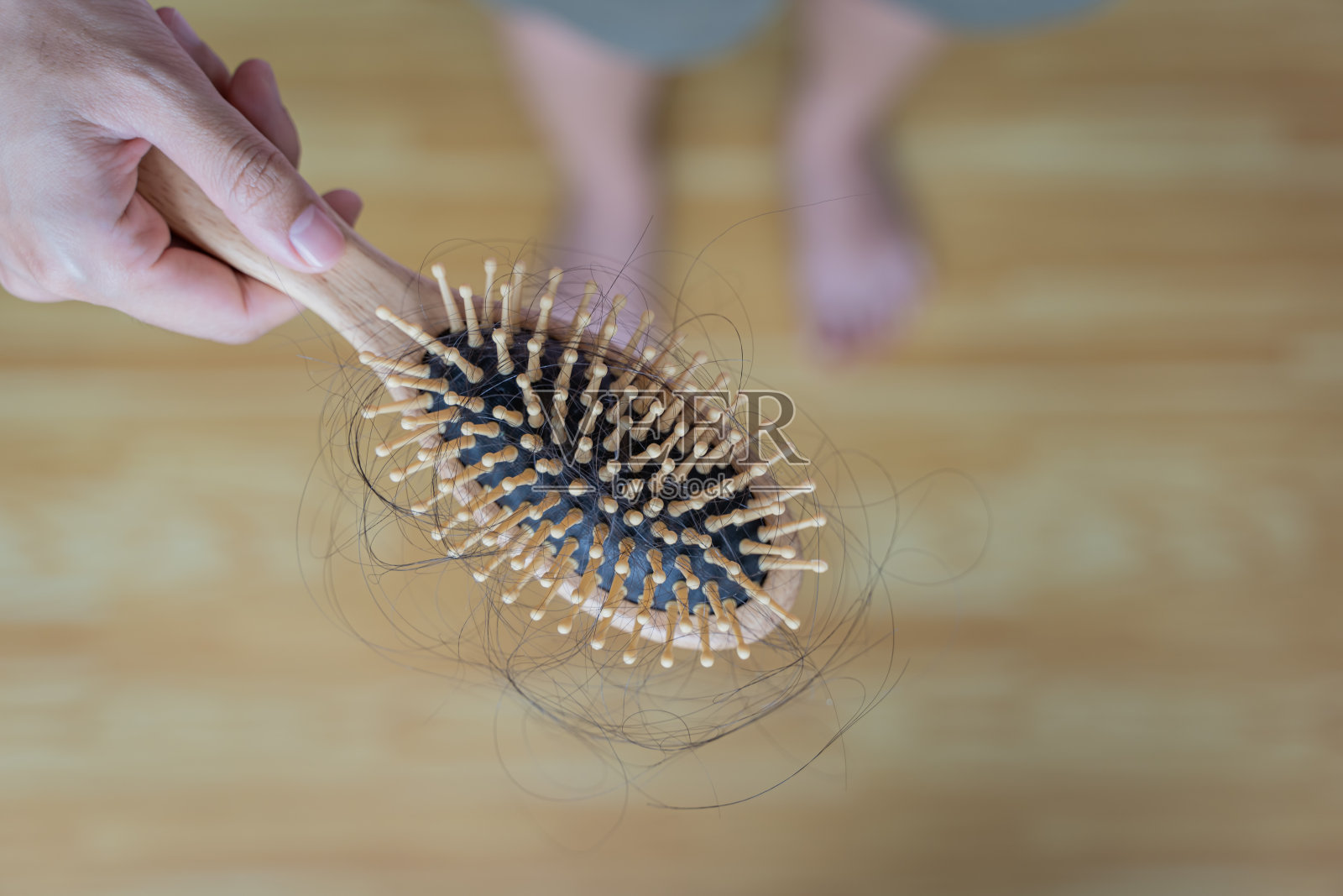 拿着梳子和头发的女人站在那里看着梳子上的头发，谈论脱发问题。照片摄影图片