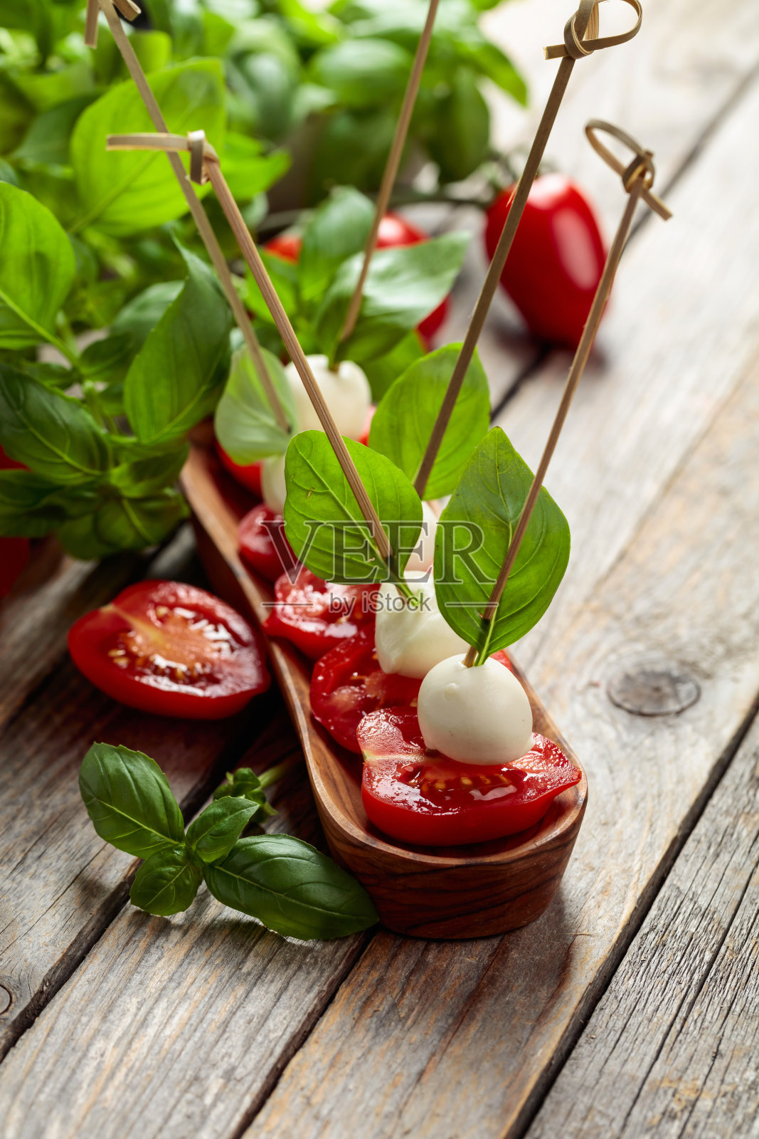 马苏里拉奶酪配罗勒和西红柿放在一张旧木桌上。照片摄影图片