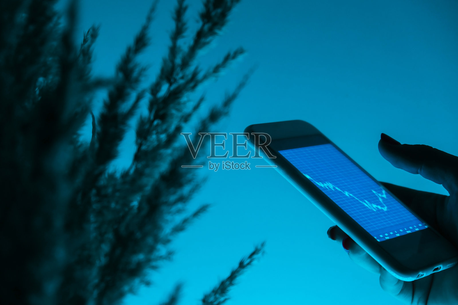 手持手机的女人，有股票市场背景的区块链，加密货币或比特币概念。夜蓝的光。未来的证券交易所照片摄影图片