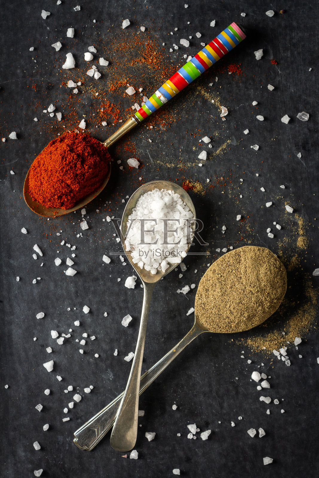 黑色背景上放着不同香料的旧金属勺子照片摄影图片