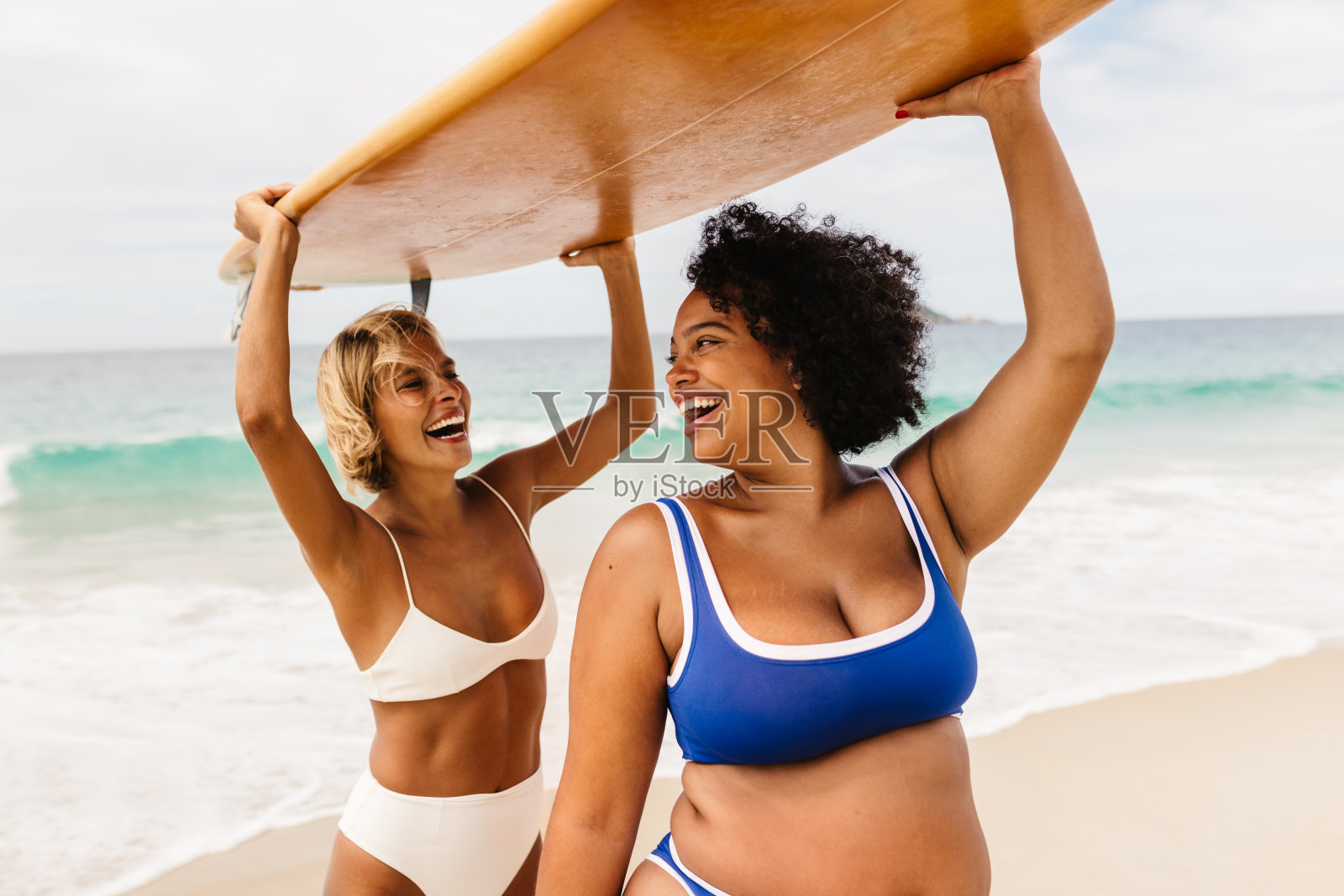 海滩冒险:快乐的朋友们拿着冲浪板在一个有趣的冲浪假期照片摄影图片