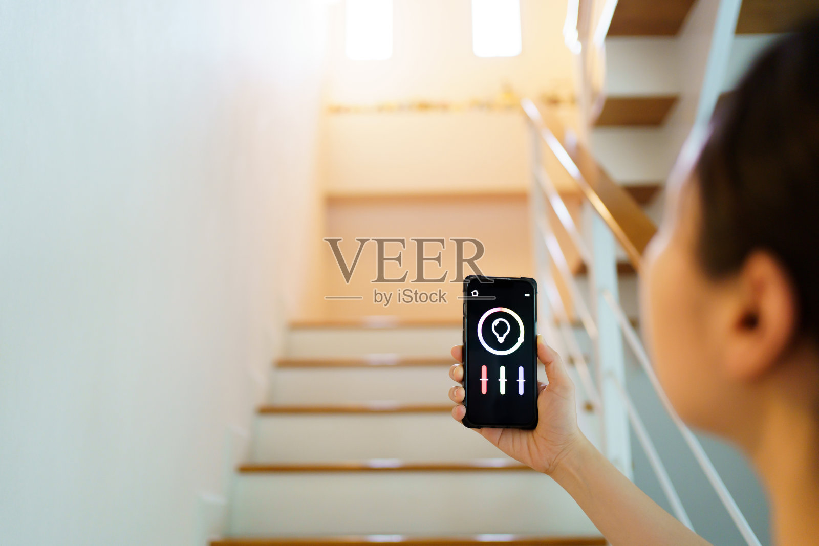 女性在智能手机上使用智能家居自动化应用程序。照片摄影图片