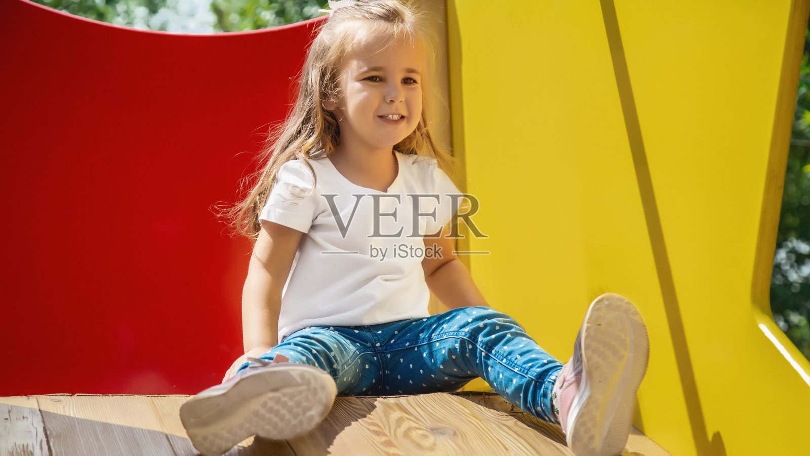 孩子在户外操场上玩耍。孩子们在学校或幼儿园的院子里玩耍。活泼的孩子在五颜六色的滑梯和秋千上。小女孩在户外。照片摄影图片