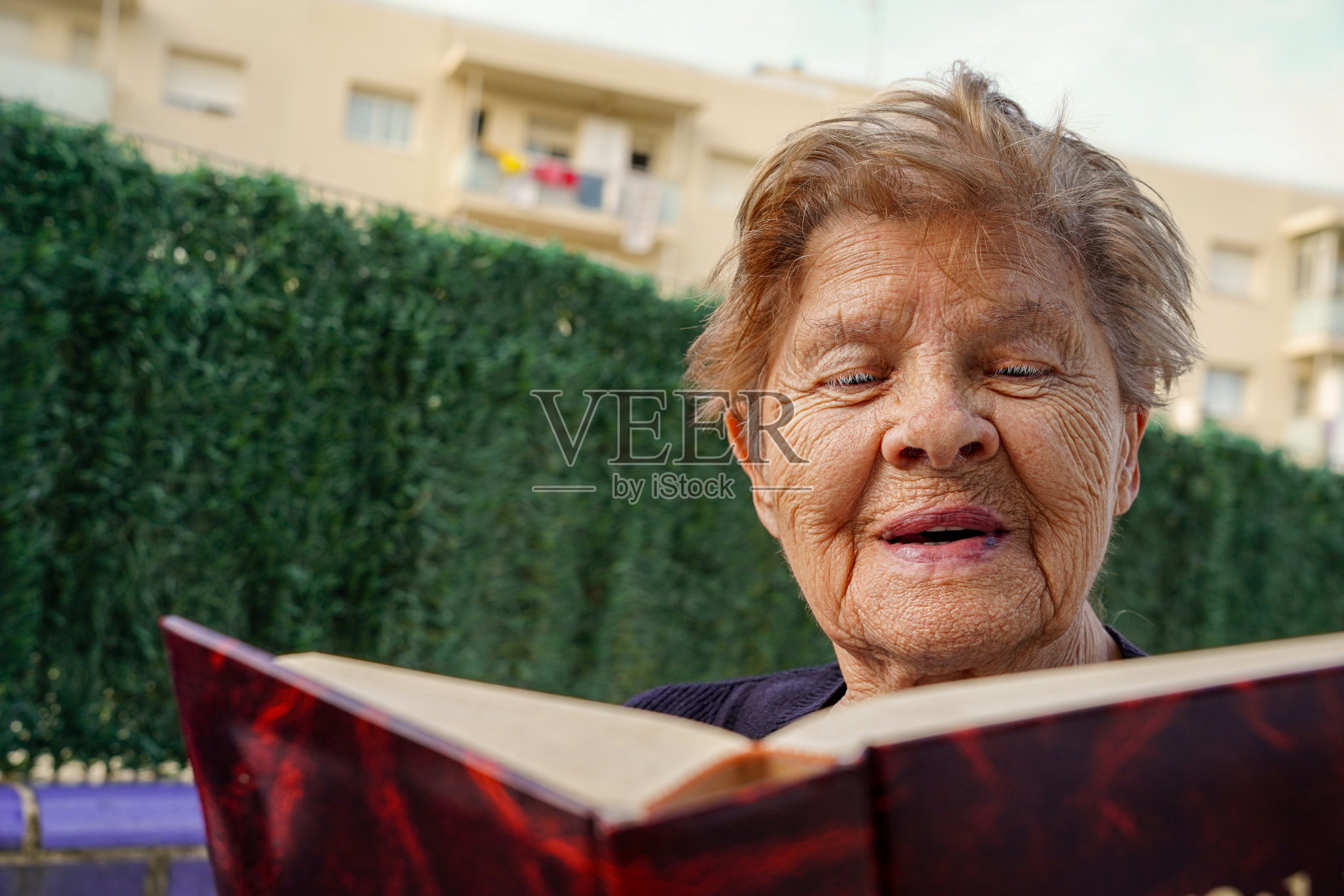 快乐的成熟女人在外面读一本畅销书。老年人生活方式积极，有爱好。老年与娱乐照片摄影图片