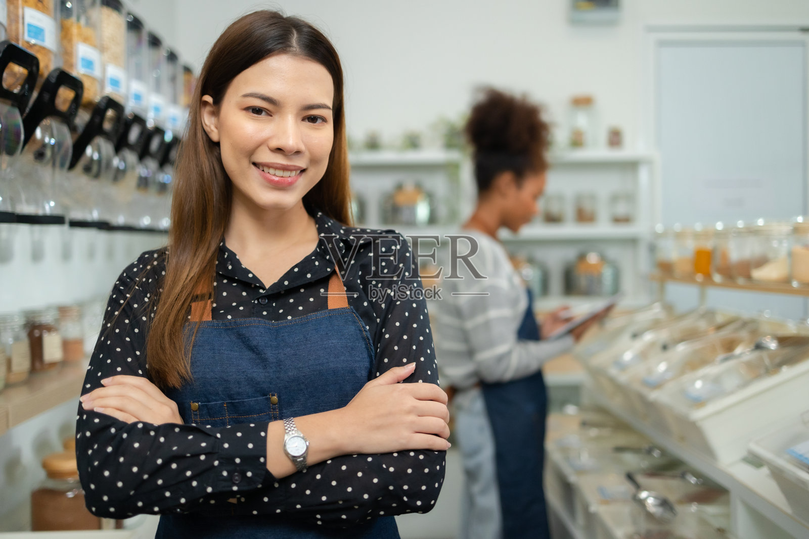 穿着围裙的年轻女老板在零废物商店里卖超级食品。无塑料意识极简主义素食可持续无塑料生活方式概念。照片摄影图片