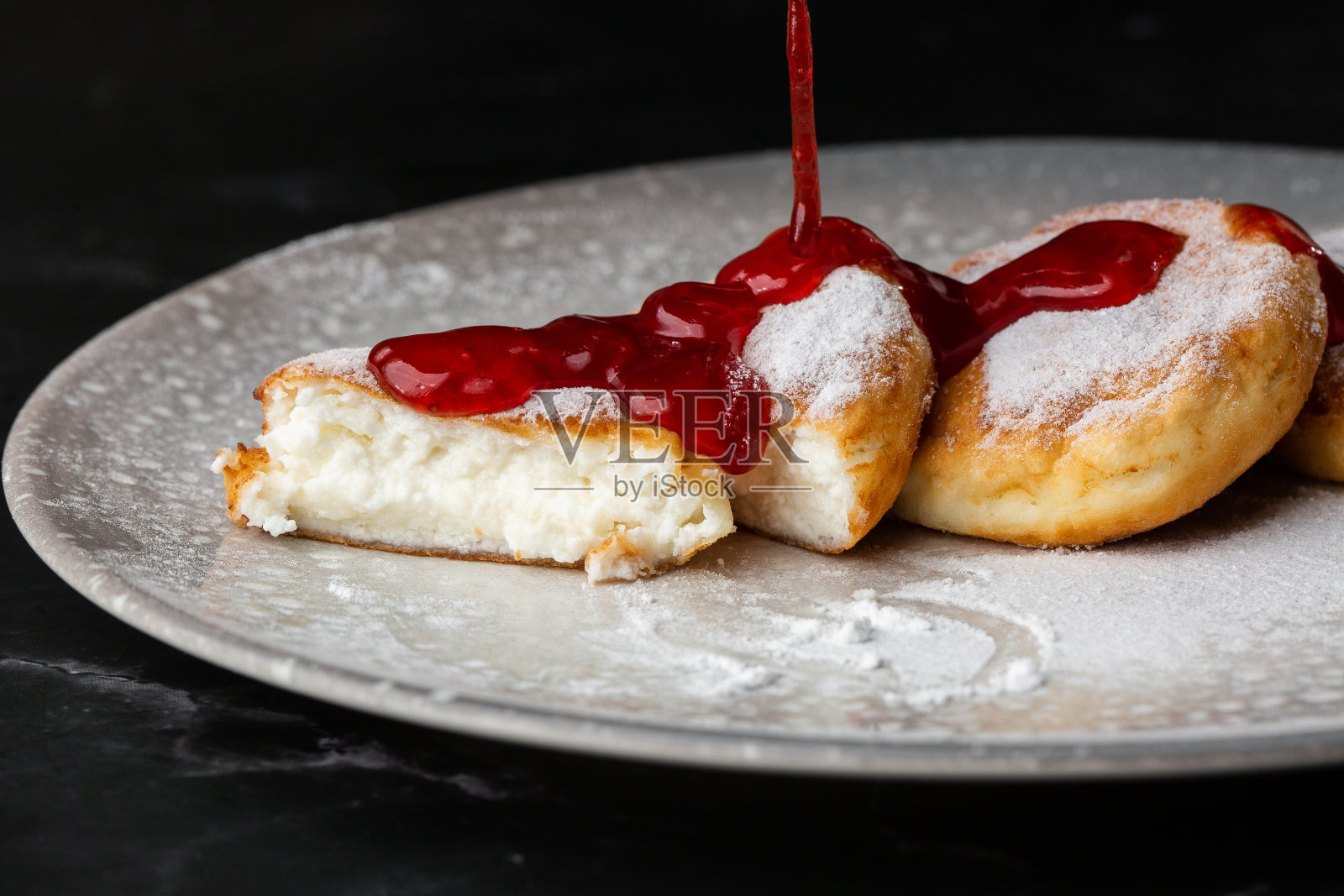 白干酪煎饼，Syrniki或奶酪蛋糕与红酱孤立在黑色大理石背景。自制的食物。美味的早餐。有选择性的重点照片摄影图片