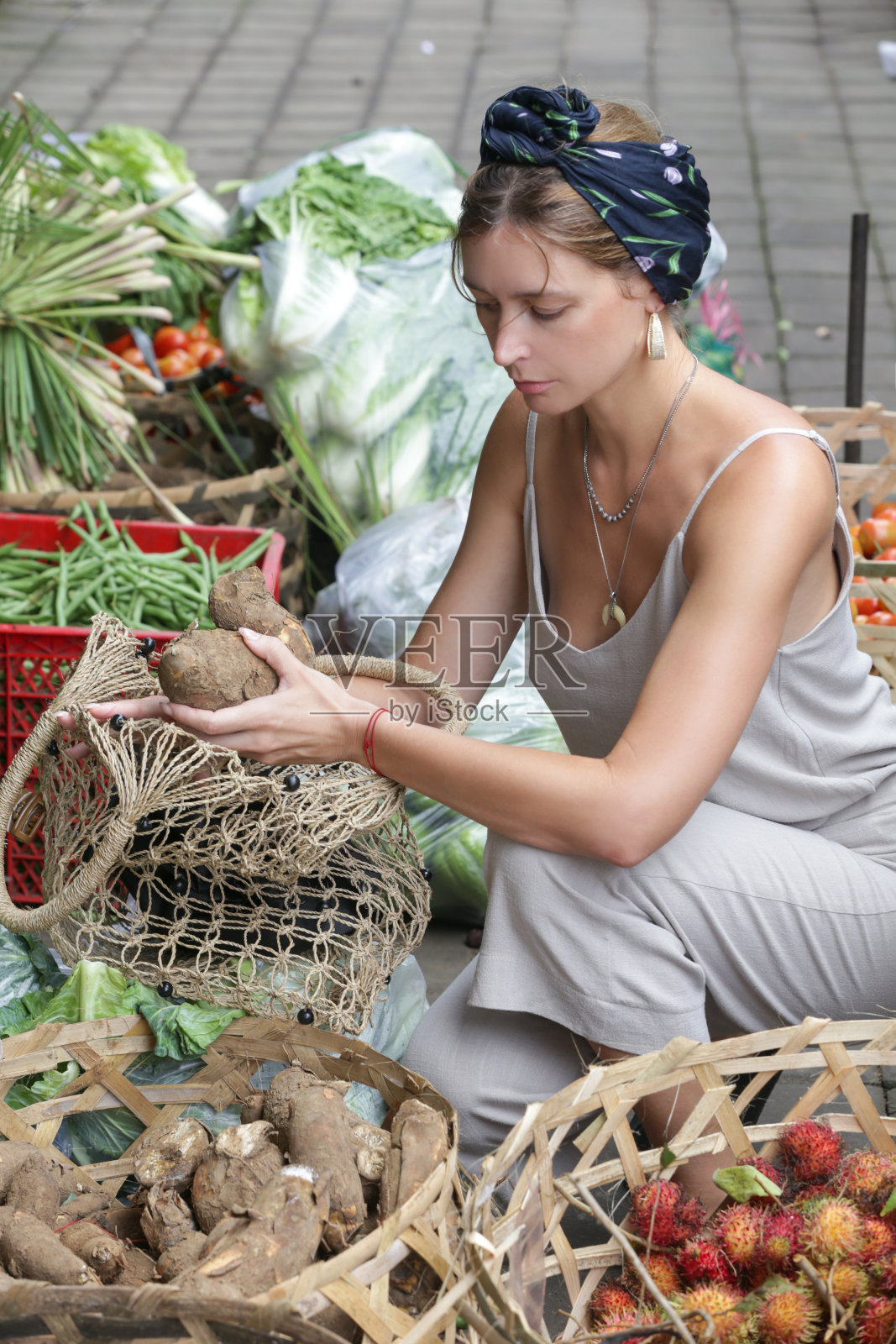 在印度尼西亚巴厘岛的当地市场买蔬菜的白人女游客照片摄影图片