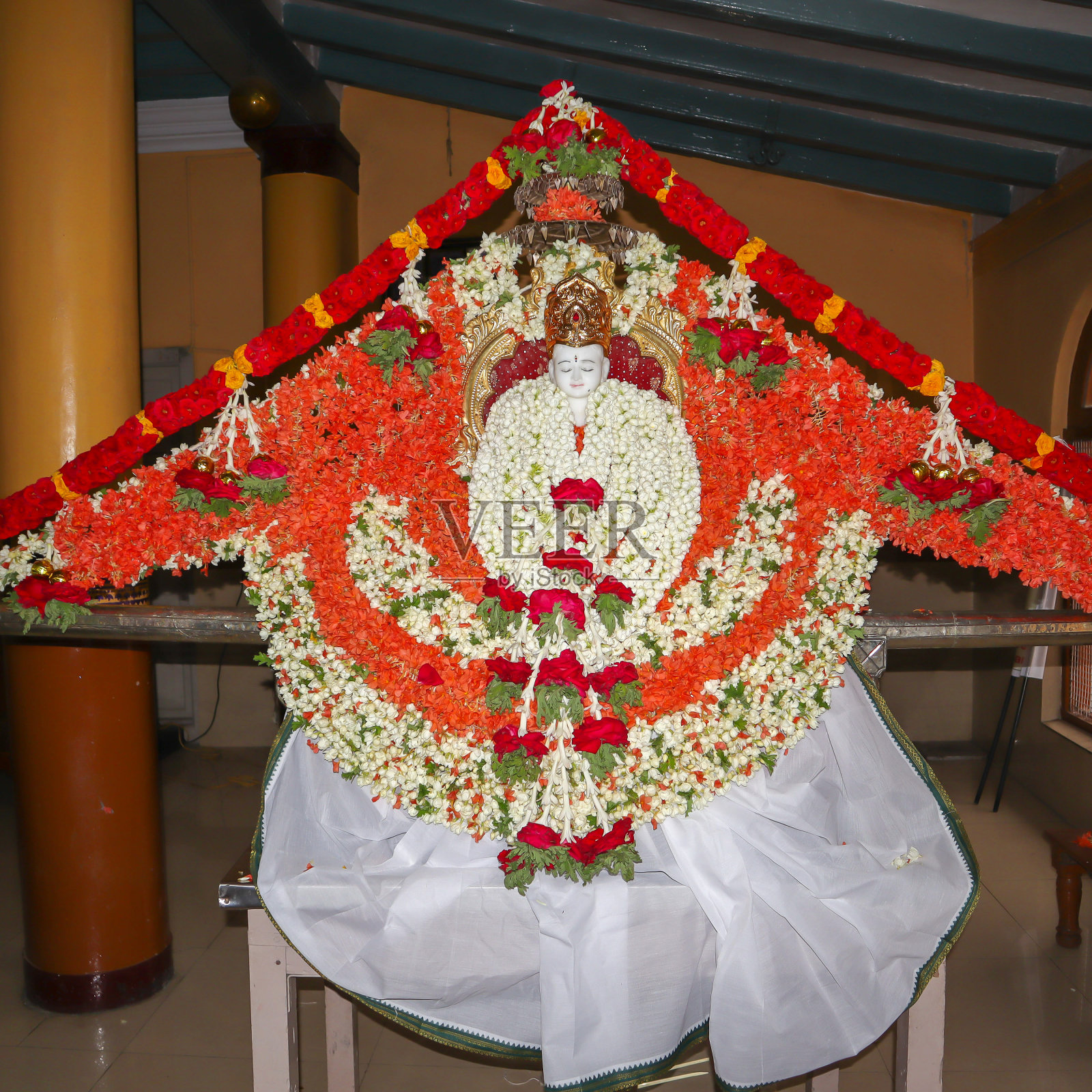 为印度迈苏鲁的摩诃佛Jayanti节而用白色大理石雕刻的大雄宝神，装饰有红色和白色的花朵。照片摄影图片