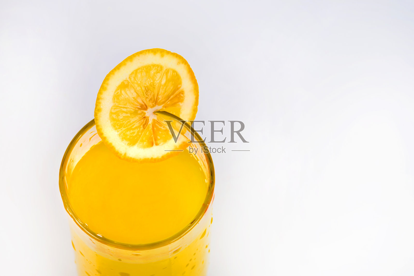 柠檬汁和一片柠檬。柠檬水在白色背景上的特写。寒冷的夏天用柠檬汁饮用。玻璃杯里的一片柠檬。照片摄影图片