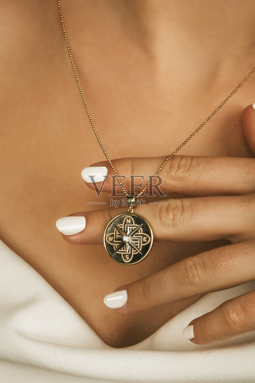 特写年轻女子穿着白色性感的缎面上衣和金项链。照片摄影图片