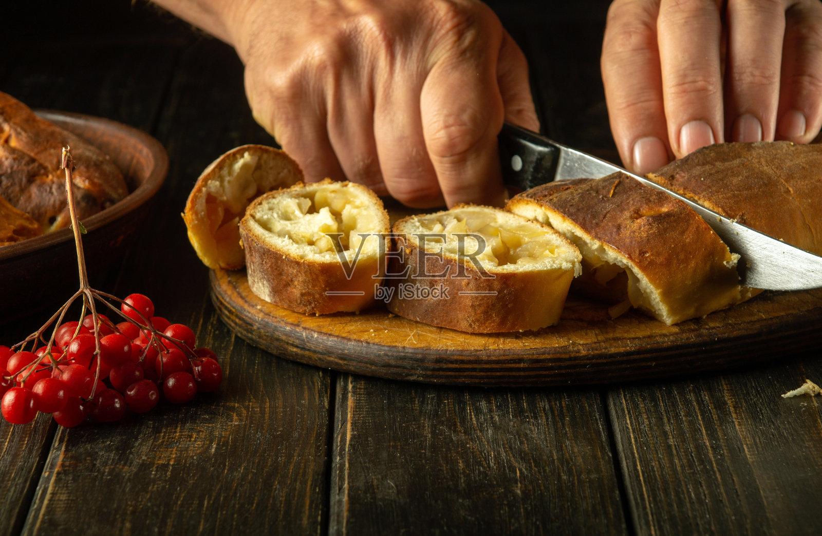 节日晚餐前，一名男子手持刀在木制砧板上切苹果派的特写镜头照片摄影图片