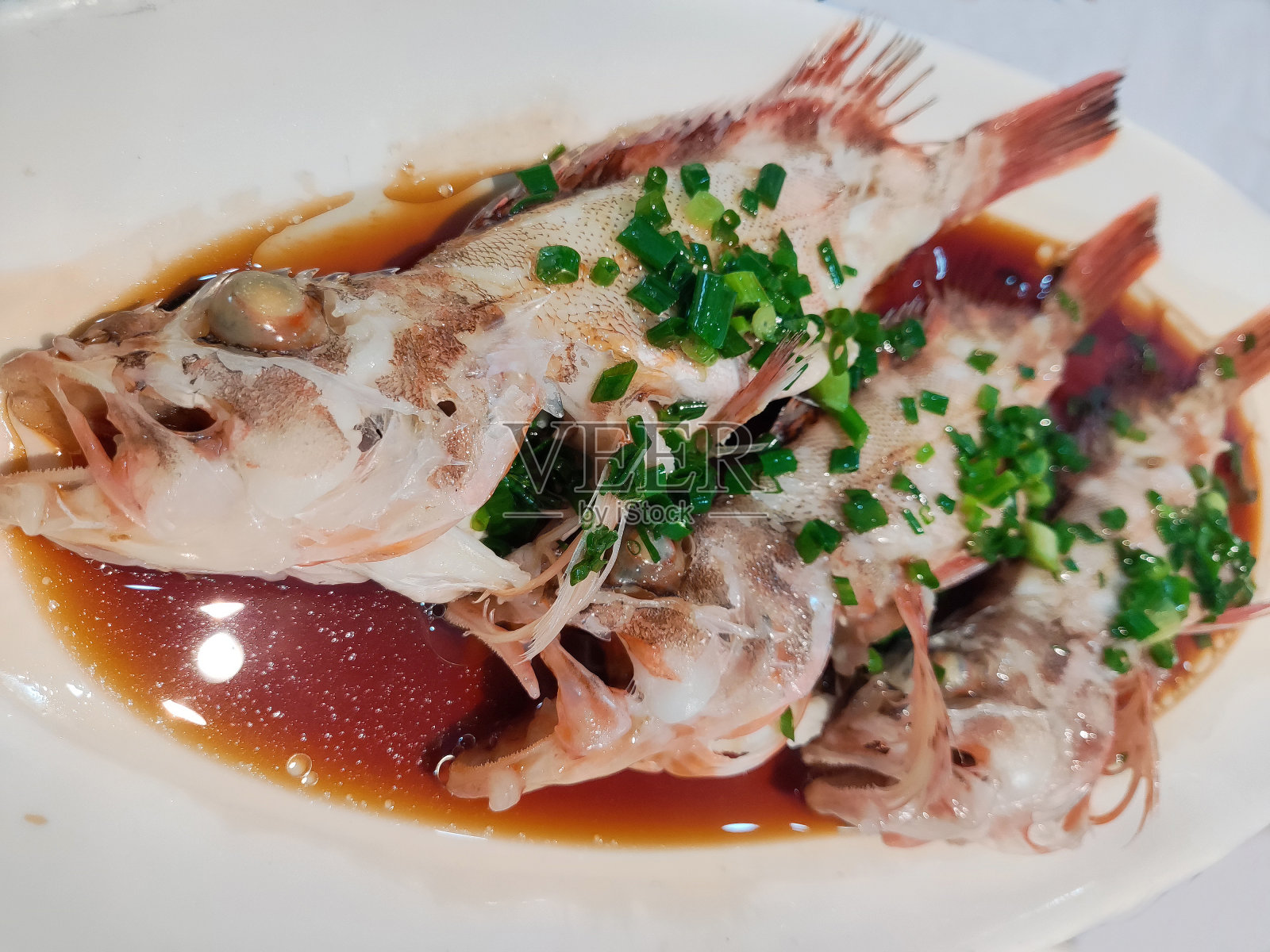 新鲜的红烧海鱼放在白色的盘子里照片摄影图片