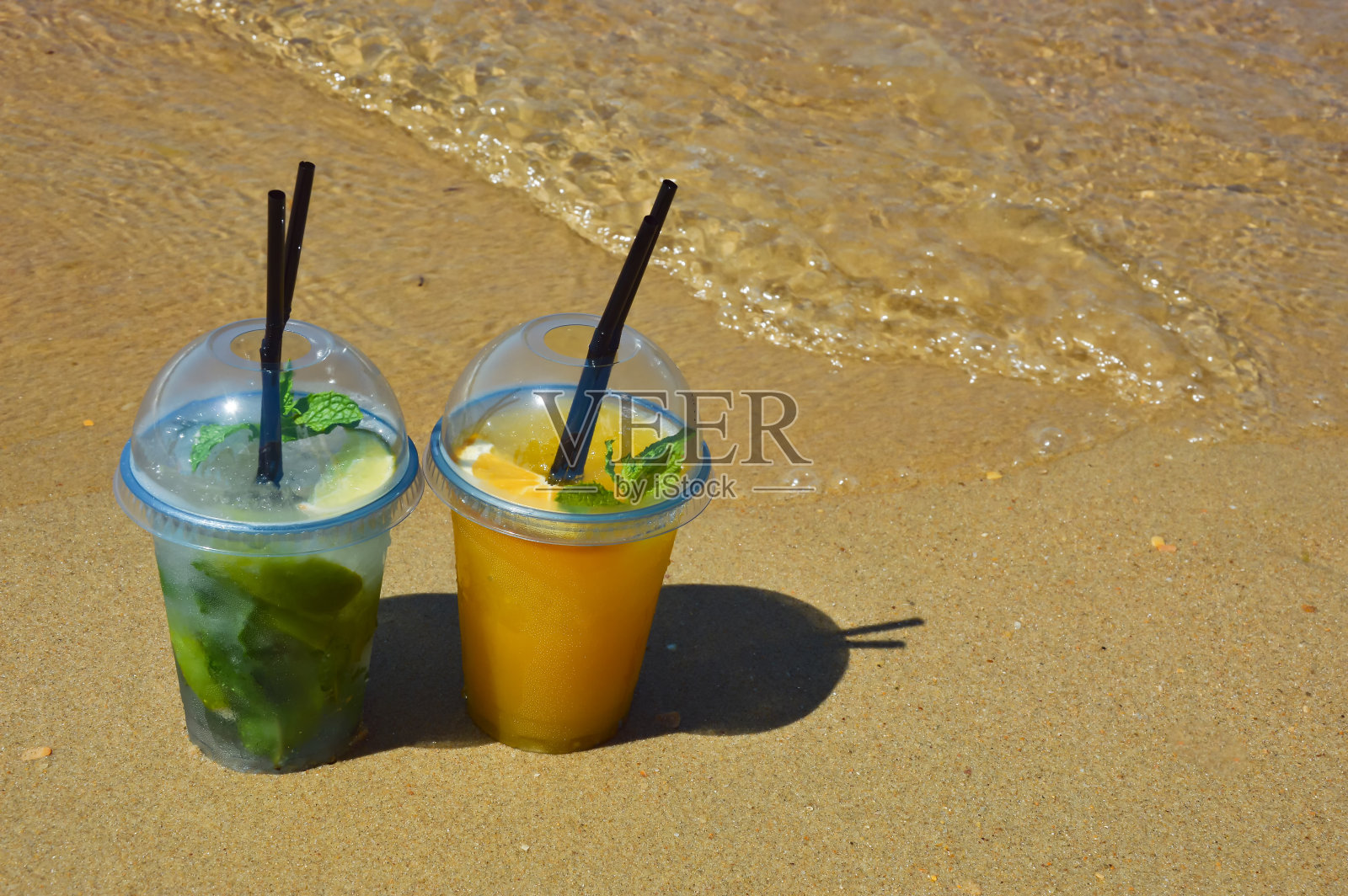 在海边，在阳光明媚的沙滩上，用吸管喝一杯柠檬水，过暑假。设计背景。照片摄影图片