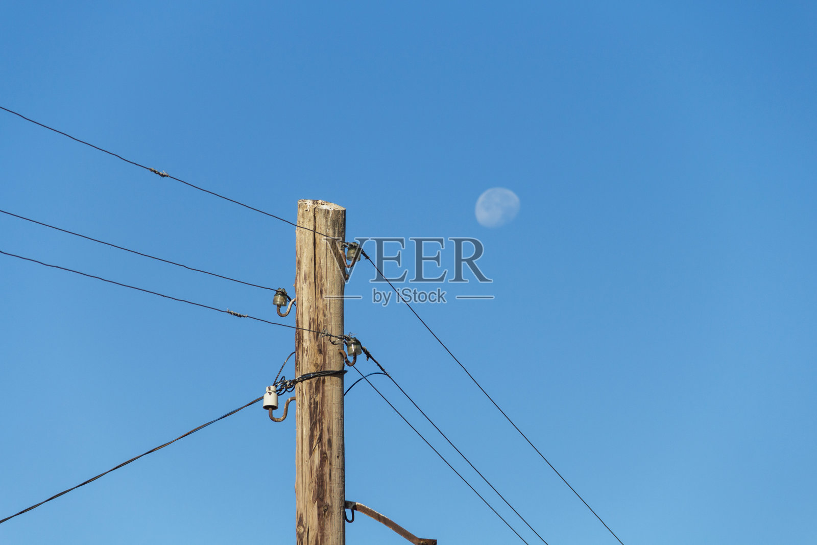 月亮映衬着一根木制电线杆。电照片摄影图片
