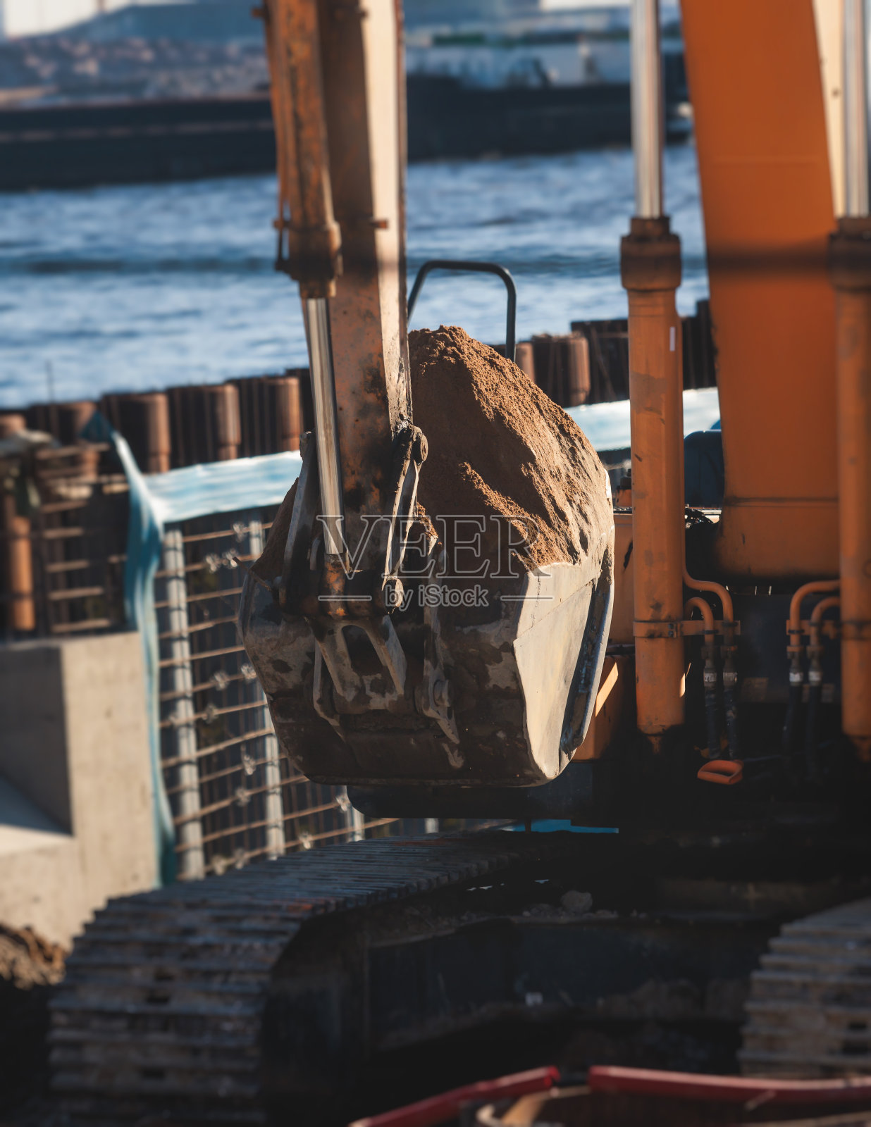 挖掘机在施工现场将沙子卸入自卸车，在道路施工期间进行挖掘和工作，反铲和自卸车卸载道路金属和砾石，施工新路照片摄影图片