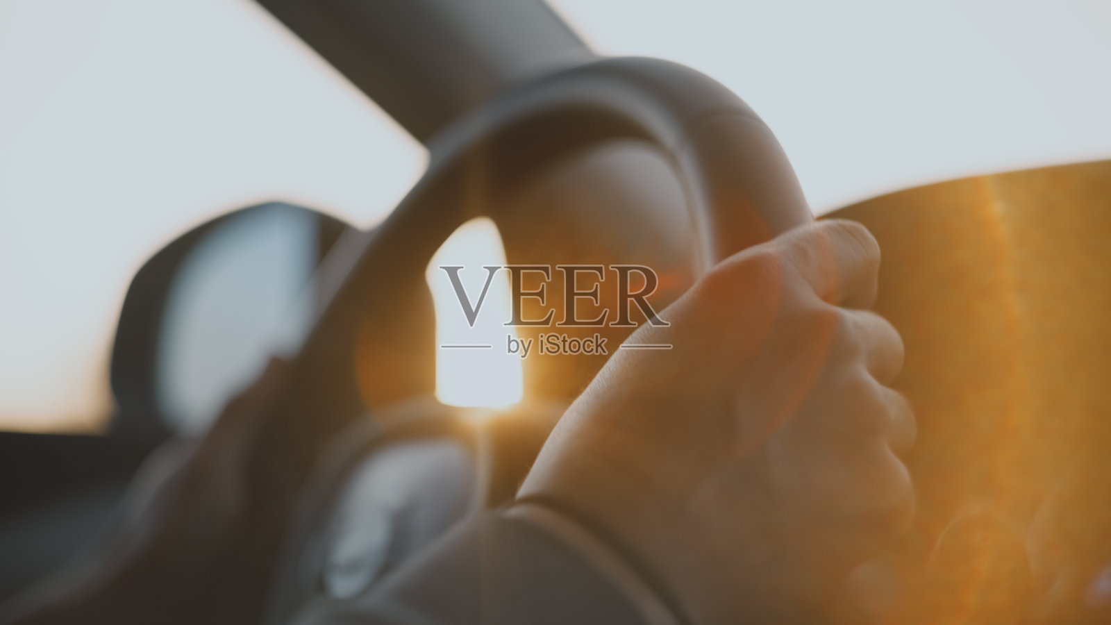 日落时分，手握方向盘驾驶汽车的人的特写照片摄影图片