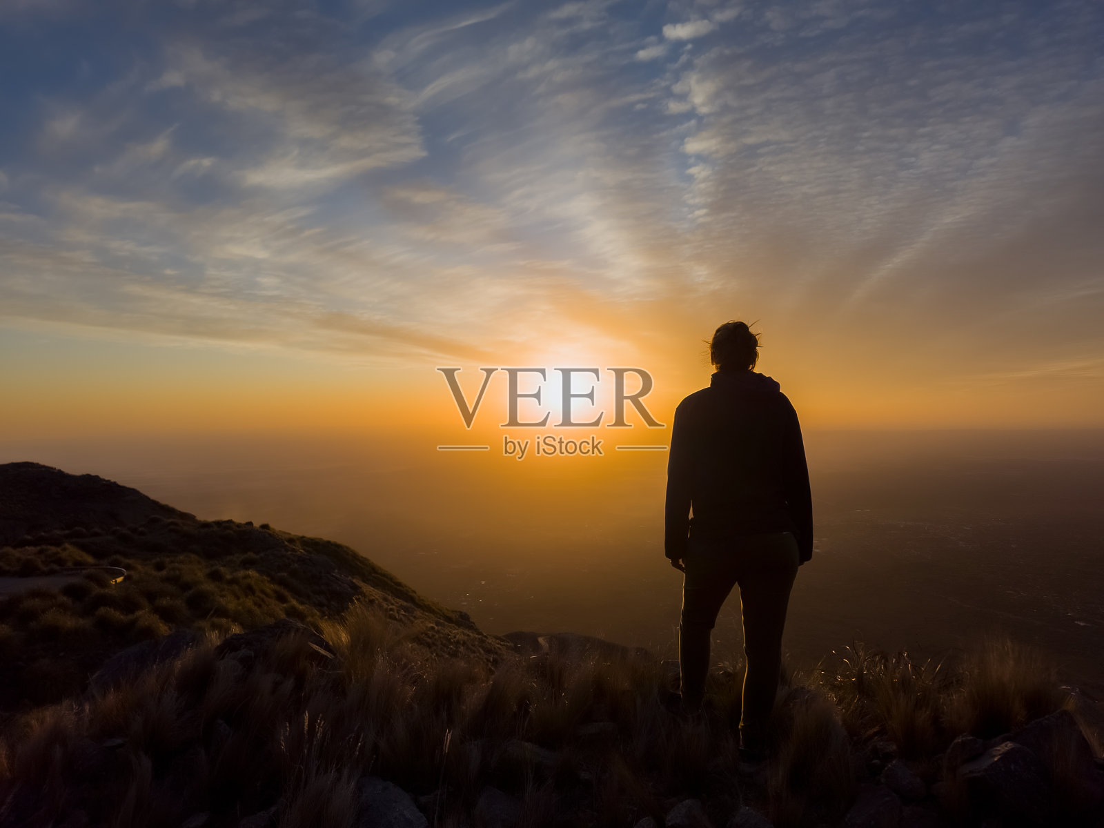 女人的剪影，在雄伟的夕阳在山上。照片摄影图片