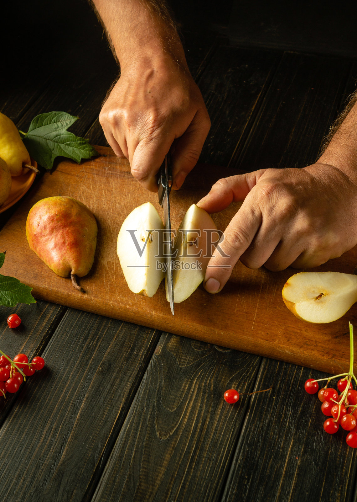 厨师在砧板上切开成熟的梨，准备果盘或果汁。梨饮食中含有一组维生素。照片摄影图片