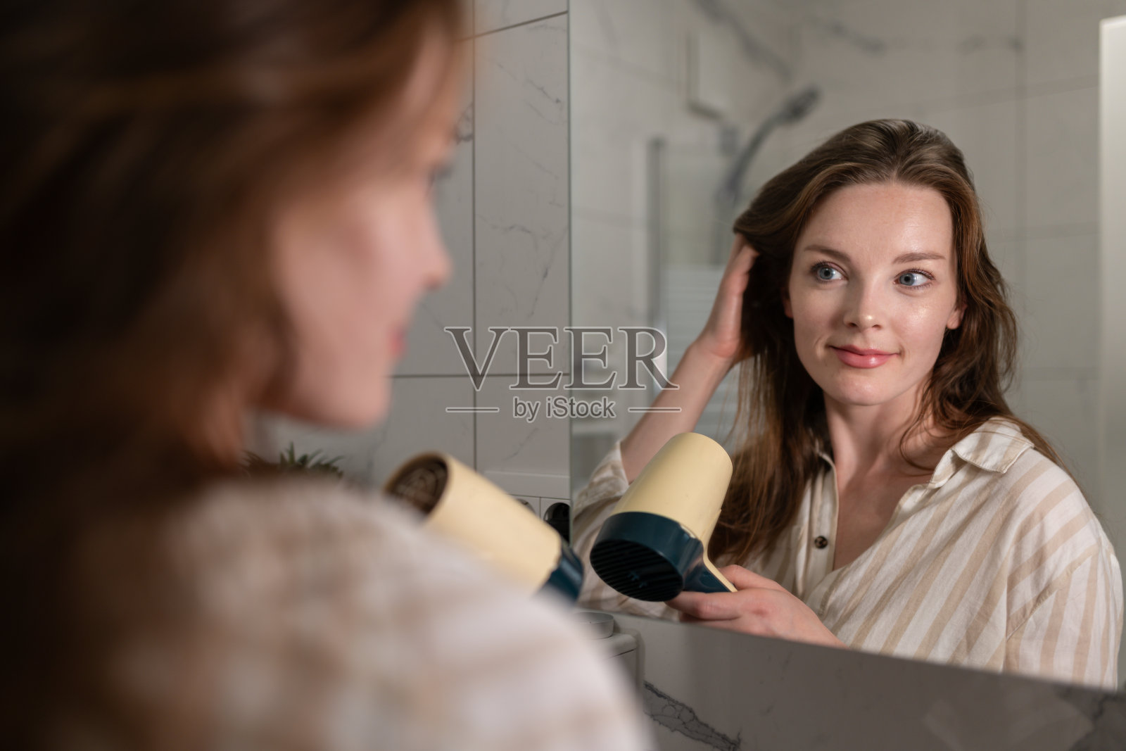 一位妇女用电吹风吹干头发照片摄影图片