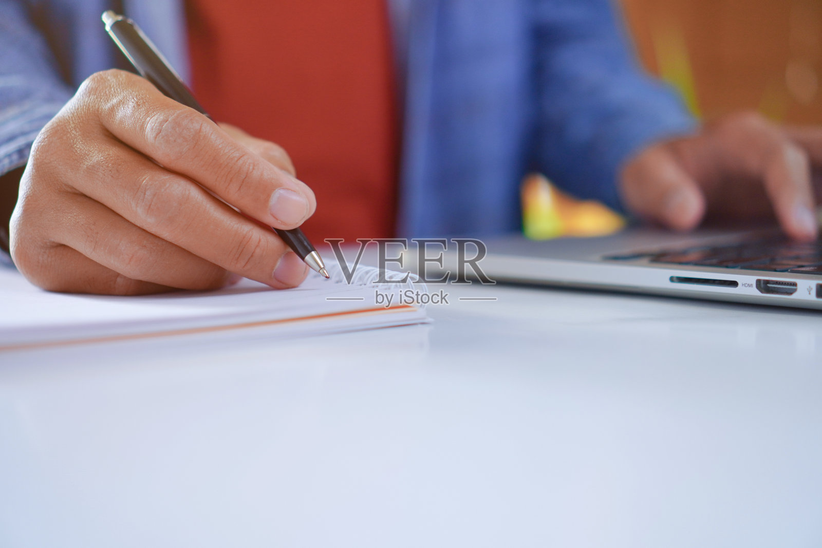 男子用笔记本电脑搜索信息，同时在笔记本上写内容照片摄影图片