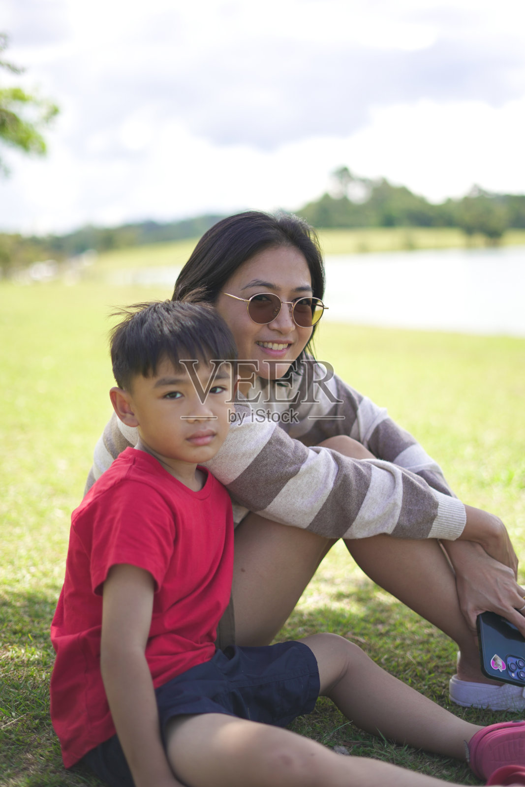 母亲和儿子坐在自然花园里欣赏风景。照片摄影图片