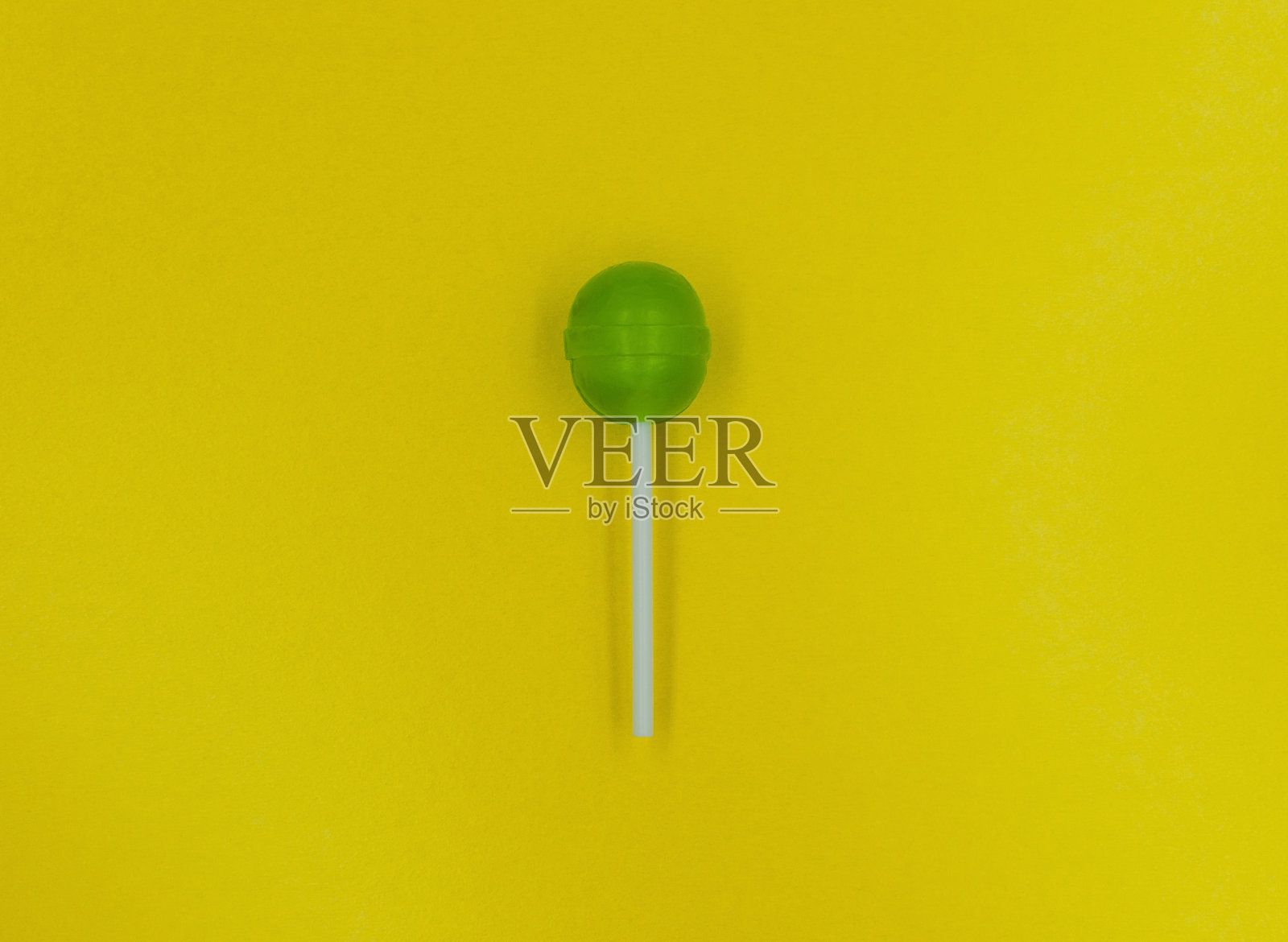 黄色背景上的绿色棒棒糖。照片摄影图片