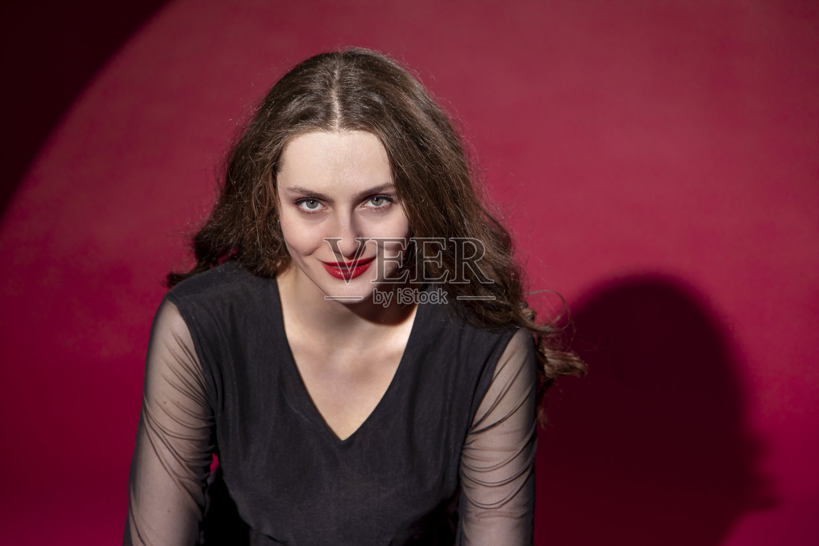一个年轻女子的工作室肖像在一个红色的背景照片摄影图片