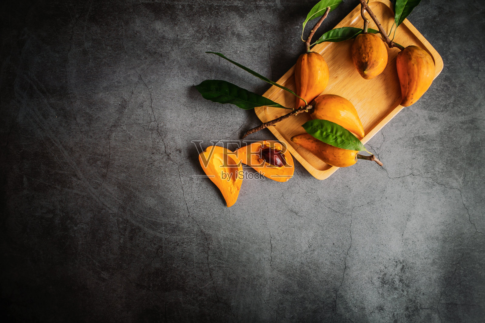 切成两半的Canistel, Tiesa，黄色仙人掌，Pouteria Campechiana,Canistel，成熟，橙色，灰色背景，俯视图，木制托盘，很多照片摄影图片