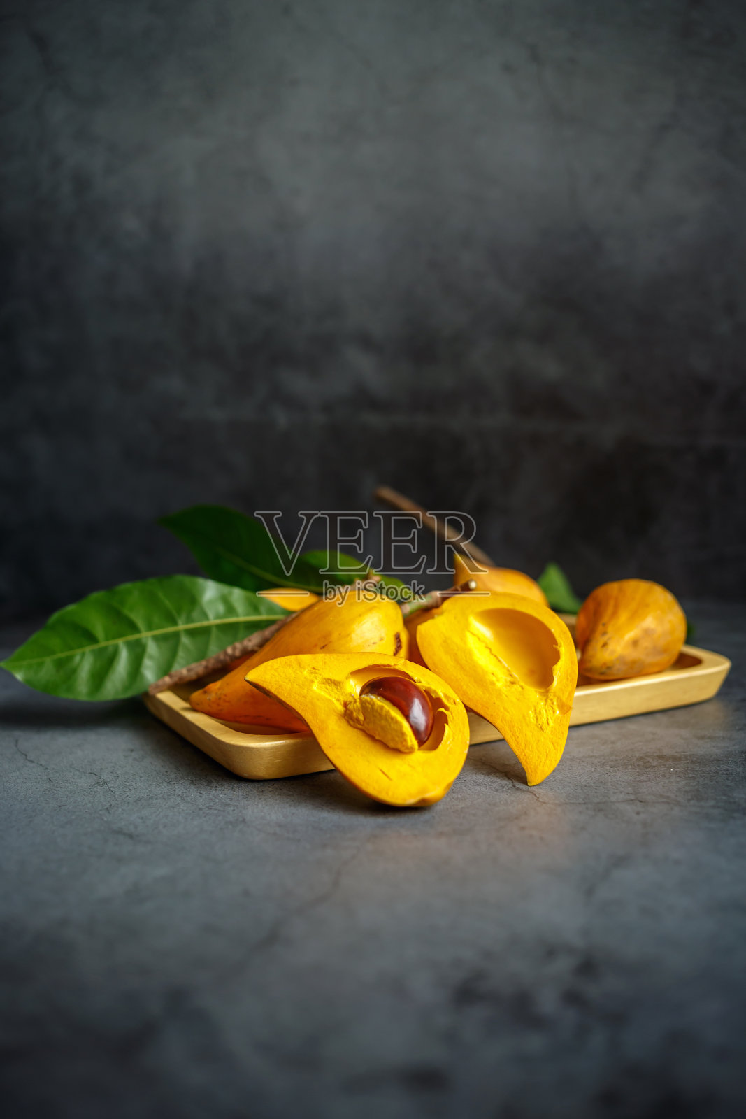 切成两半的Canistel, Tiesa，黄色仙人掌，Pouteria Campechiana,Canistel，成熟，橙色，灰色背景，特写，木制托盘，很多照片摄影图片