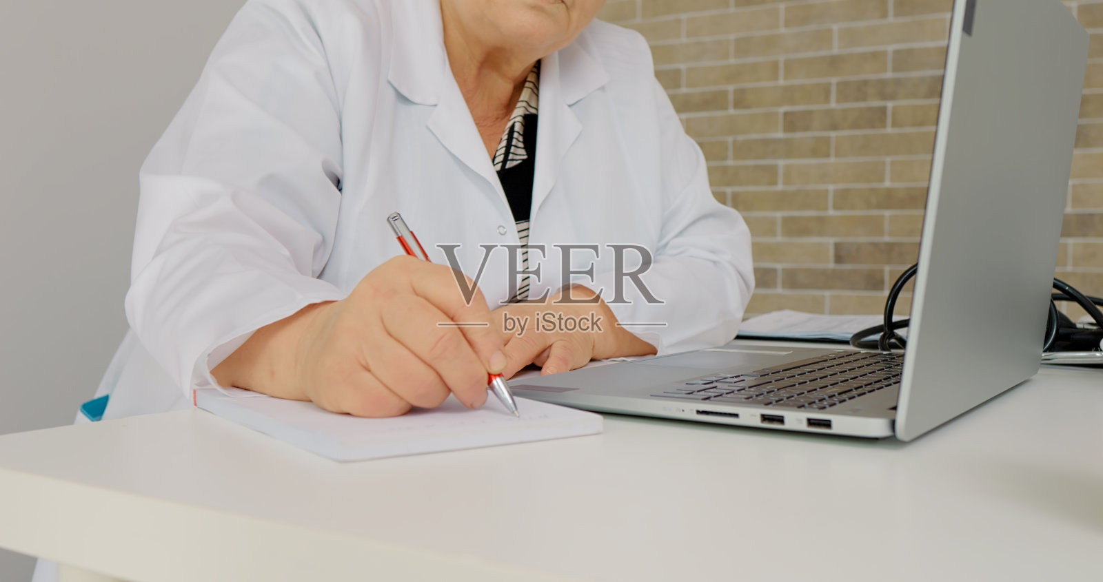 资深医生正在从一封通过电子邮件发送的医疗信函中做笔记。照片摄影图片