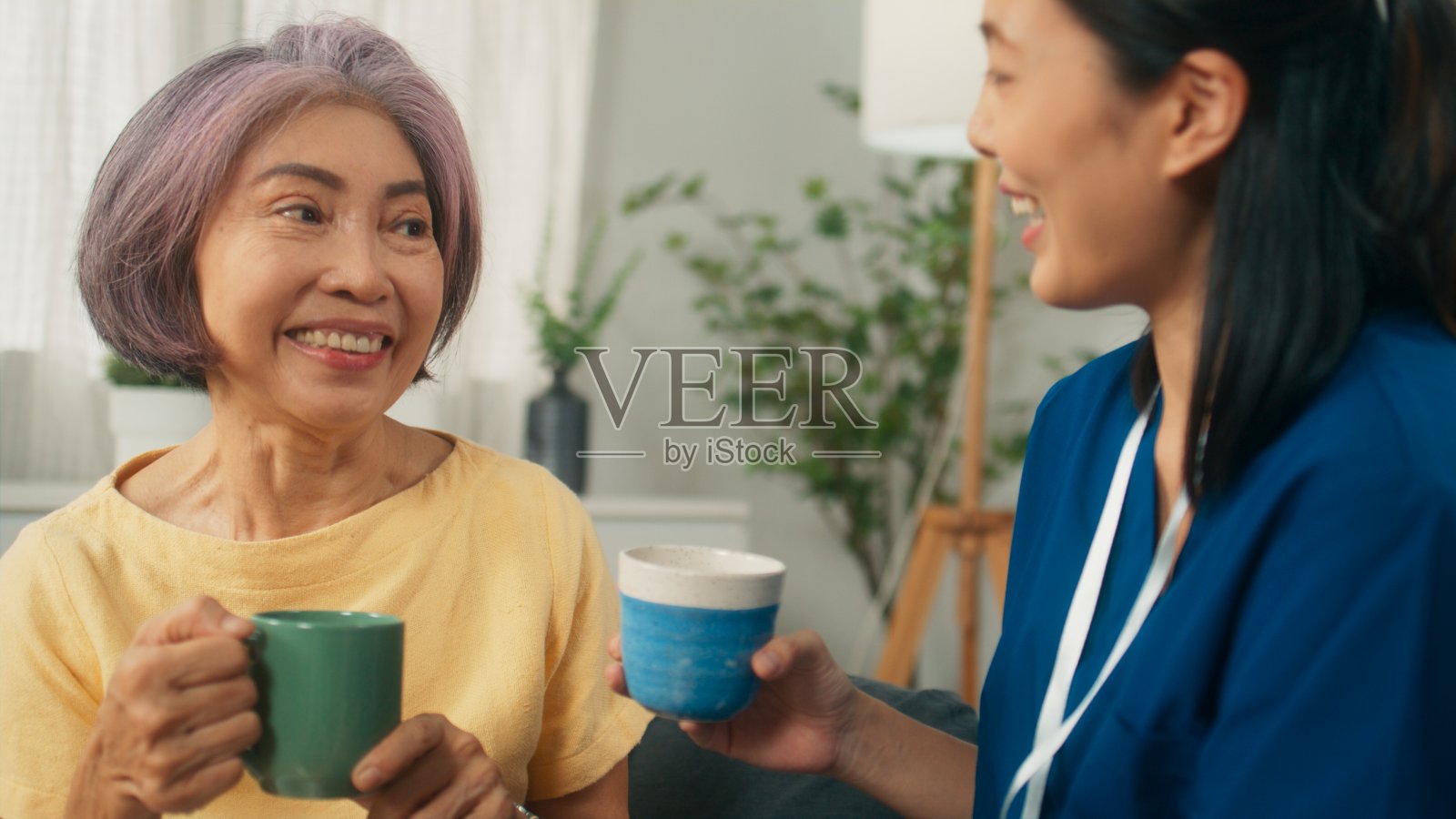 家访时，保健专家在客厅与快乐的女病人聊天，一起喝茶照片摄影图片