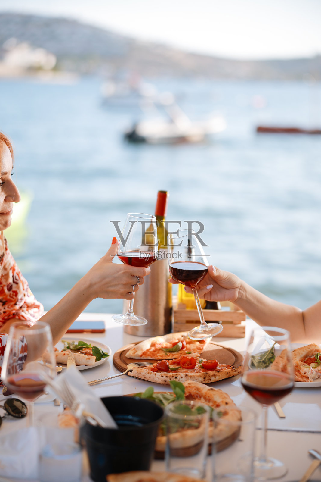 两位女性朋友在夏日街咖啡馆外面的露台上笑着喝酒的特写照片摄影图片