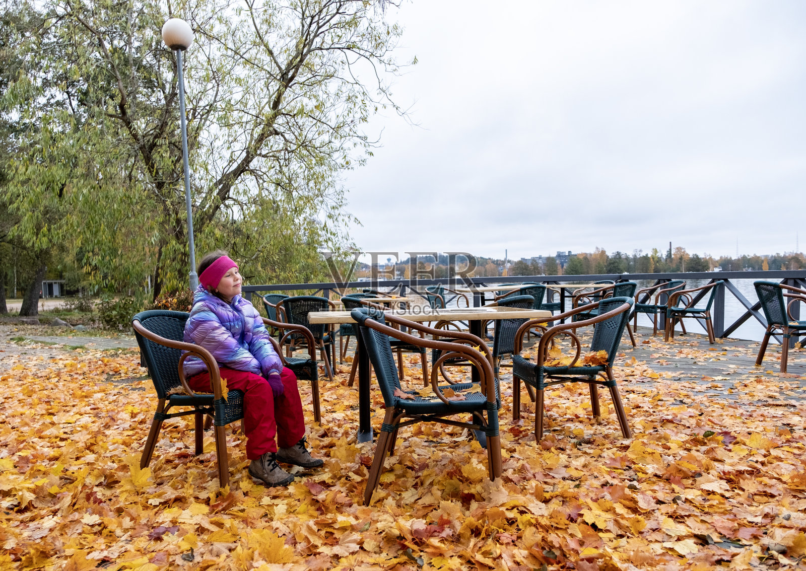 孩子，女孩，8岁，在秋天散步。他坐在咖啡馆外一张桌子旁的椅子上，享受大自然，做梦。照片摄影图片