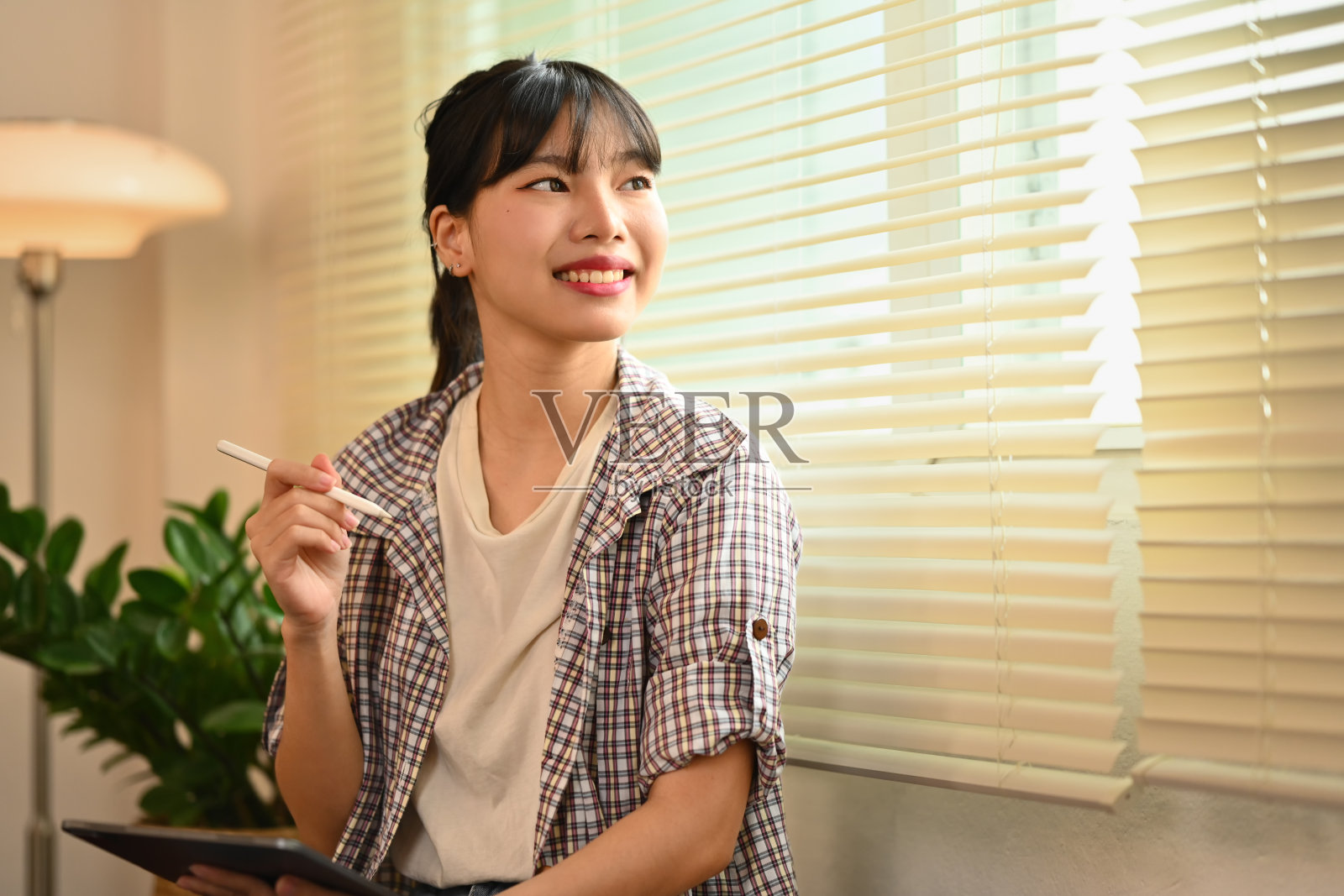 美丽的年轻女子拿着数码平板电脑，望向远方，梦想着美好的未来照片摄影图片