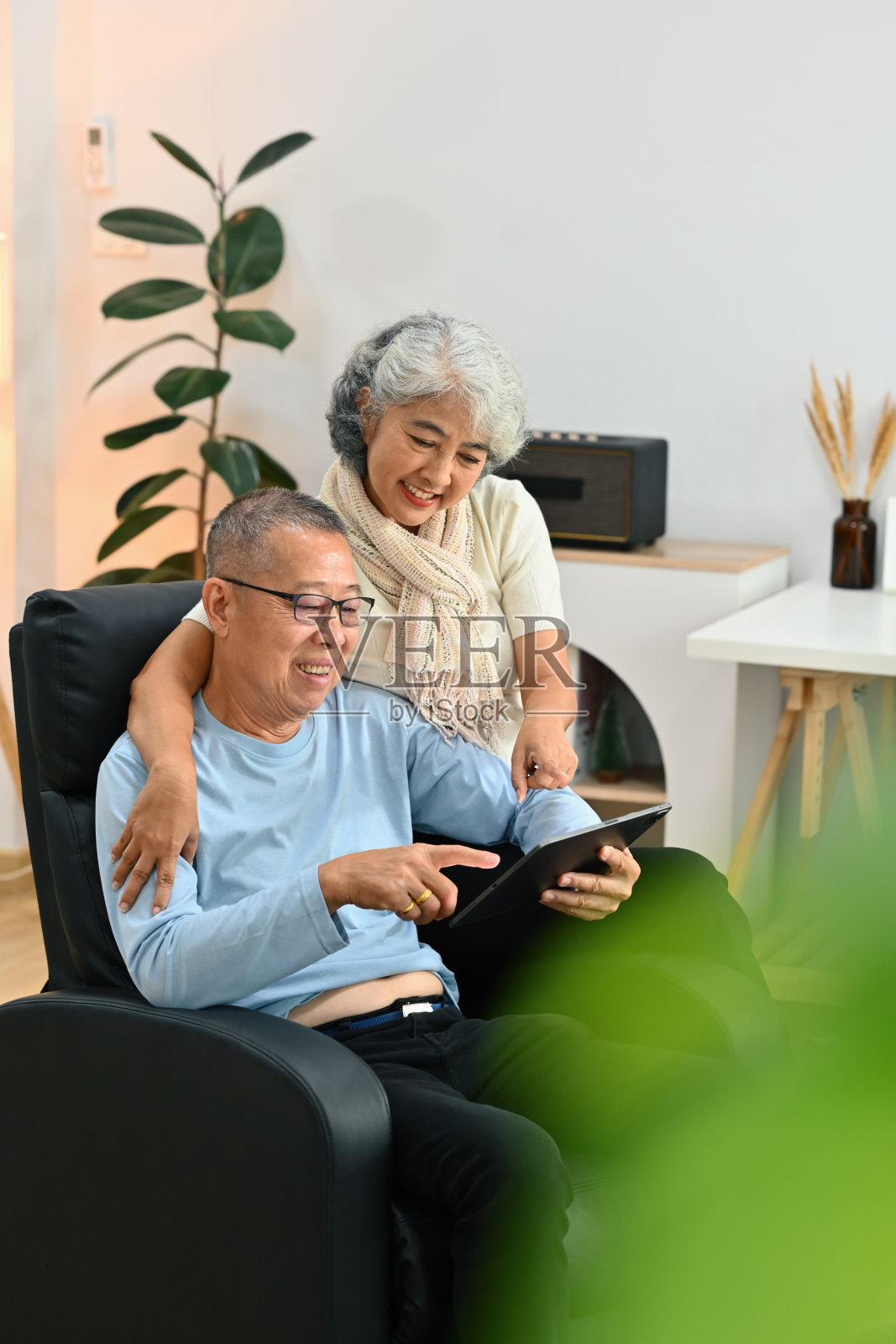 幸福的老年夫妇穿着随意，在家里用平板电脑上网照片摄影图片