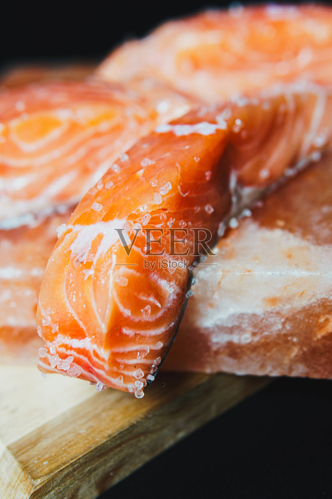 新鲜的生三文鱼片，在喜马拉雅盐块上加调味料和香草照片摄影图片