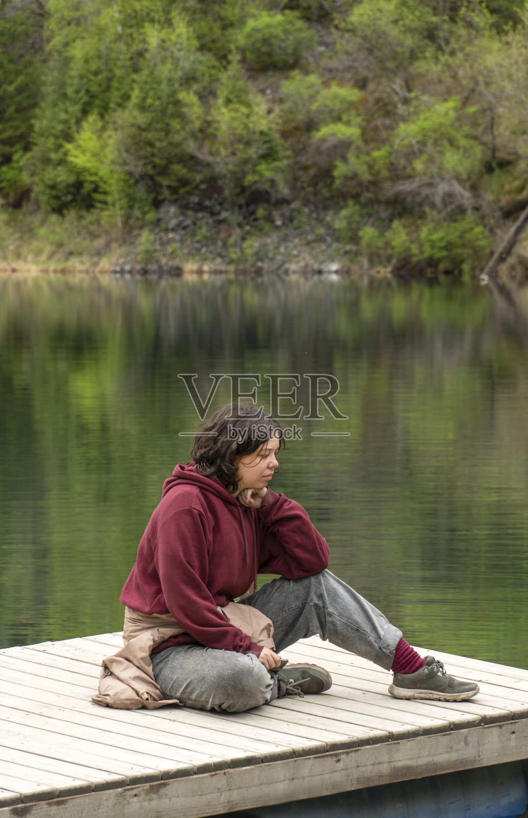 年轻女子坐在湖边的木制码头上做梦照片摄影图片