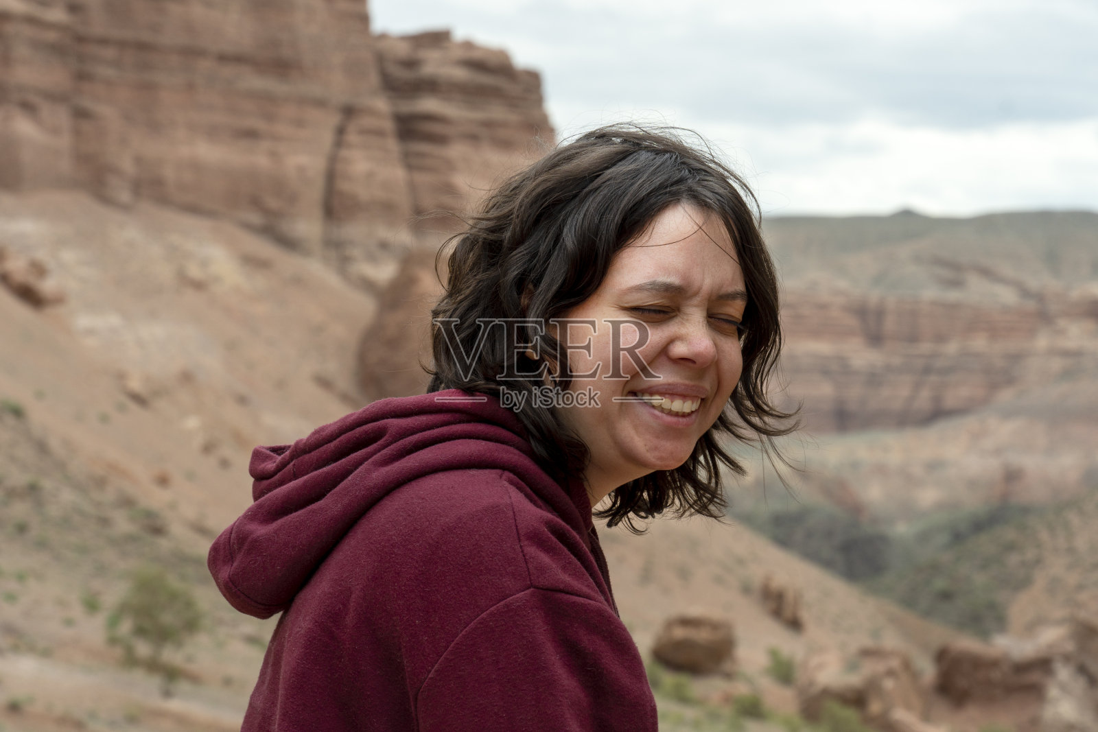 一位年轻女子坐在中亚大峡谷的一块岩石上照片摄影图片