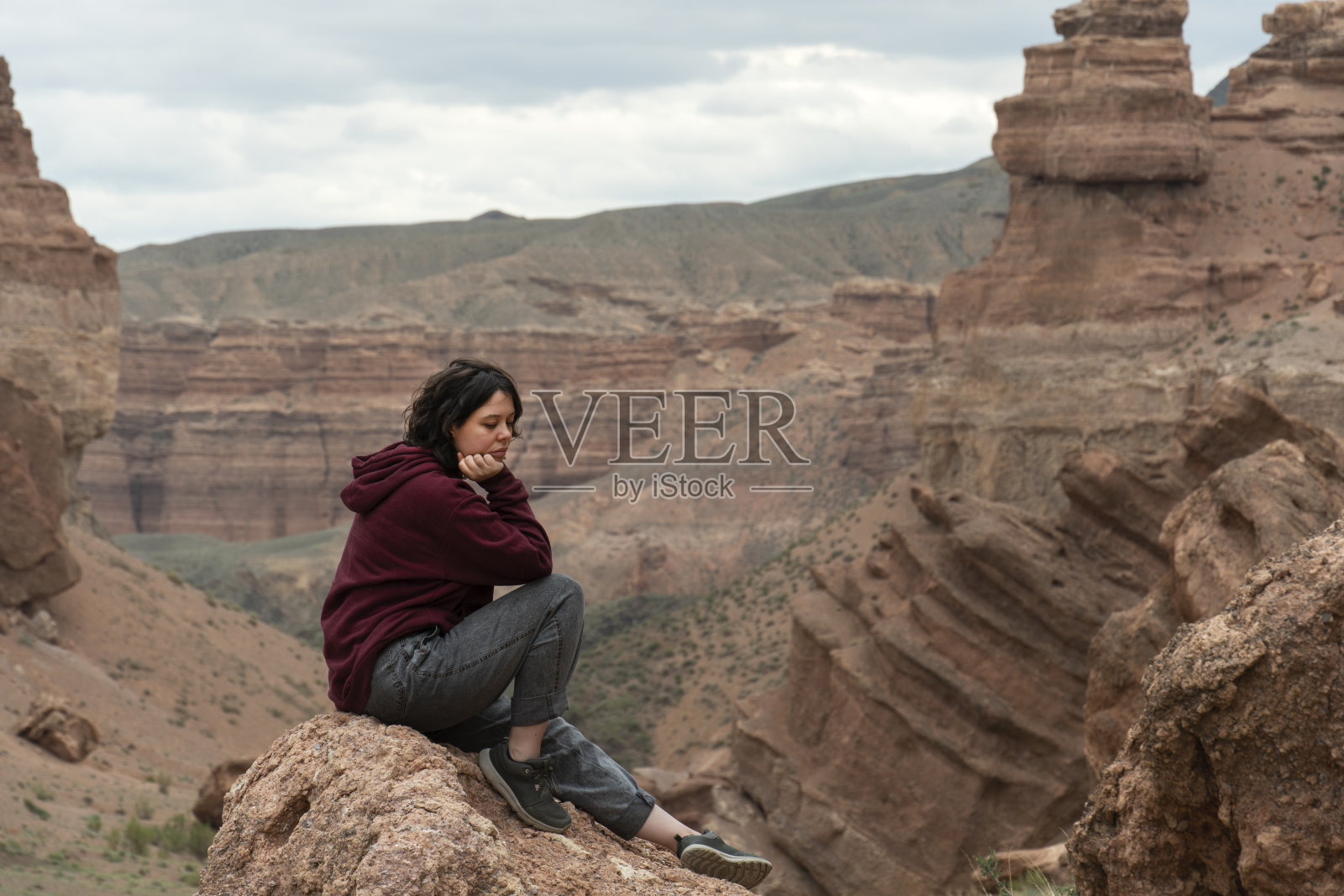 一位年轻女子坐在中亚大峡谷的一块岩石上照片摄影图片