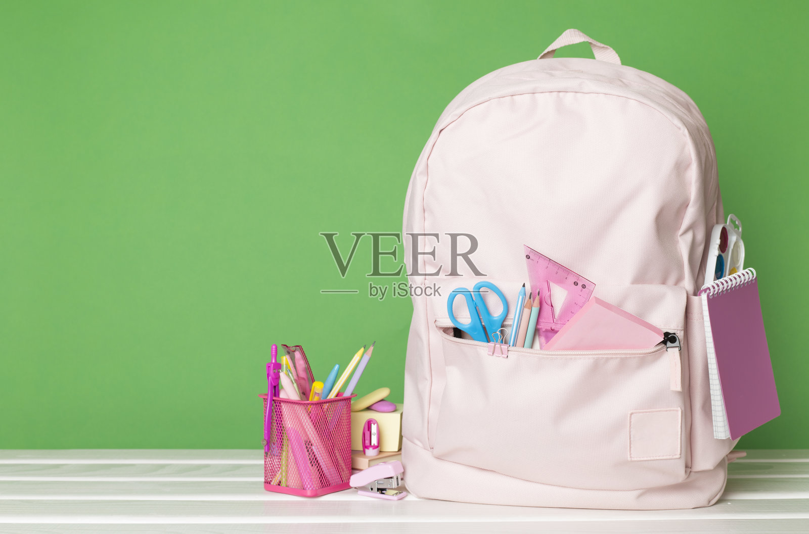粉红色的学校背包，木桌上放着文具照片摄影图片