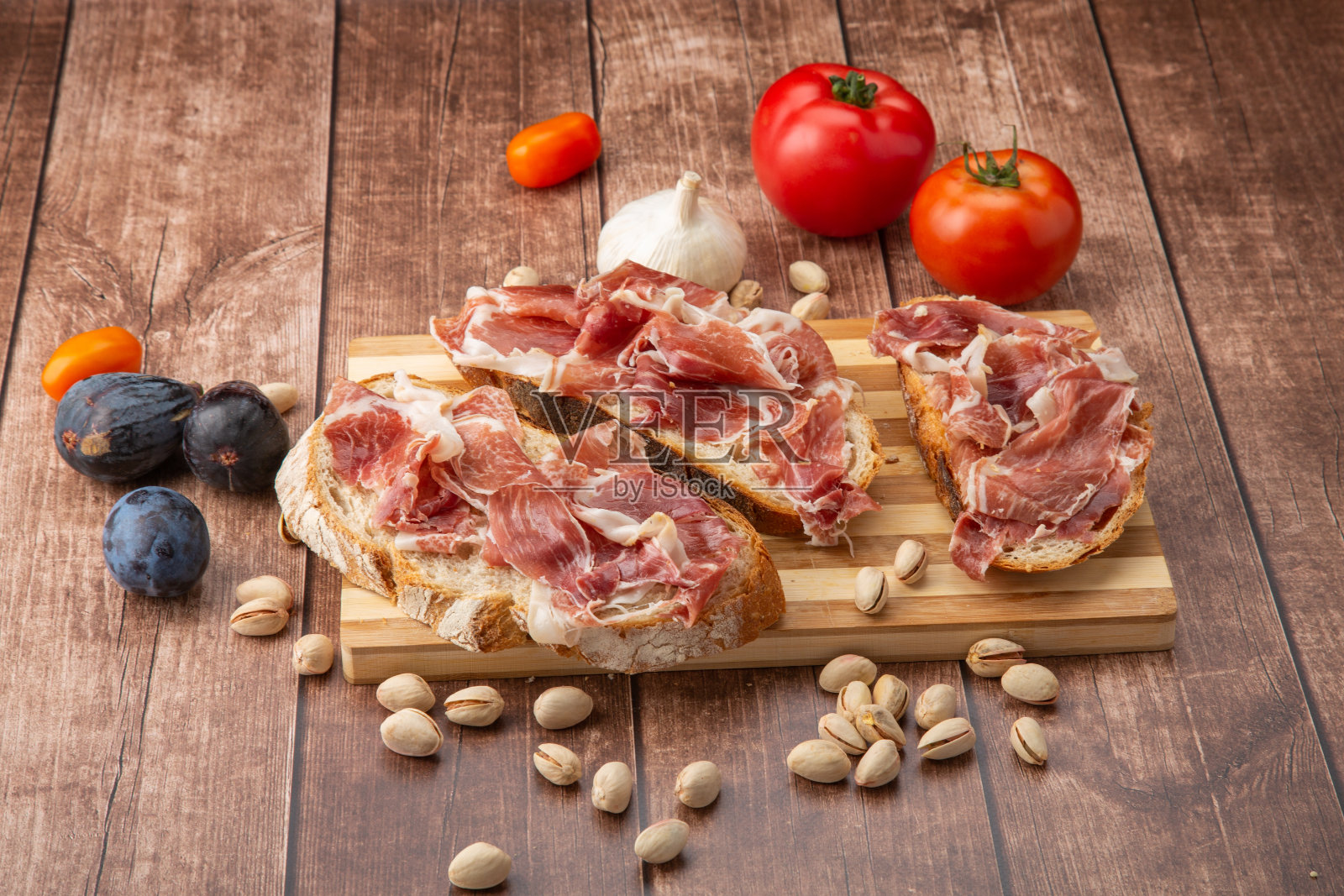 伊比利亚火腿放在质朴的木头上，美味佳肴。照片摄影图片