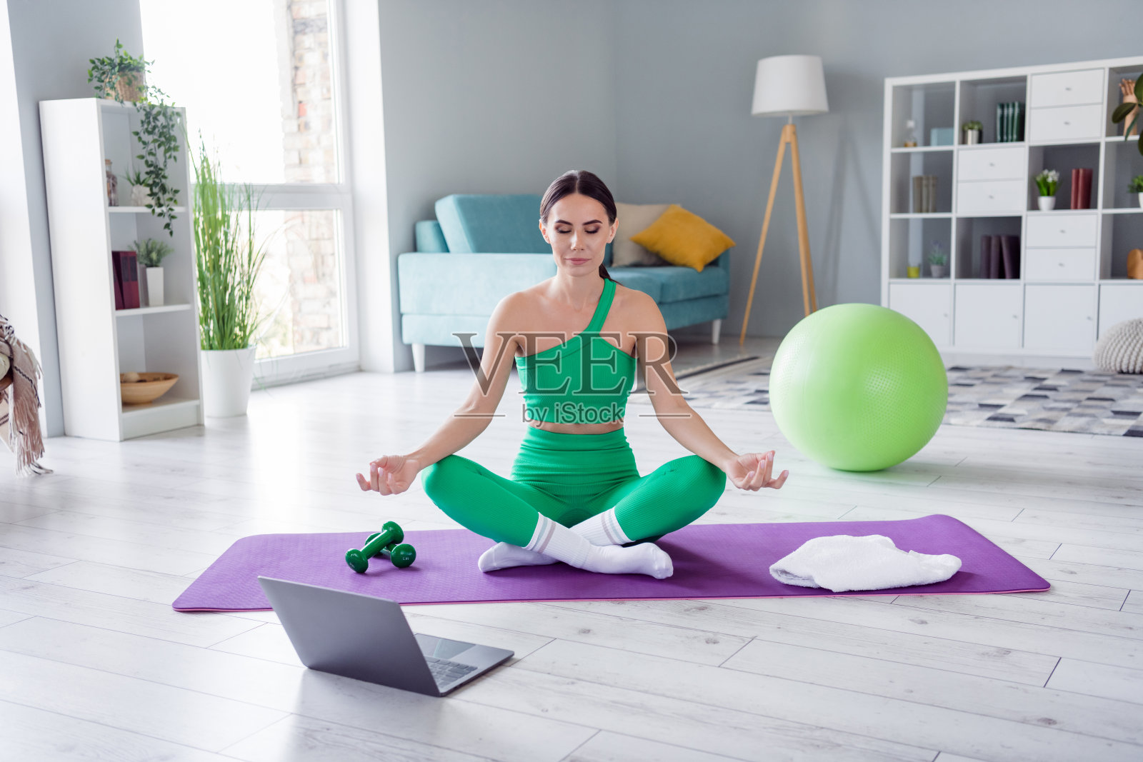 照片甜美闪亮的女孩穿着运动服坐在垫子上看视频瑜伽课在家里的房子照片摄影图片
