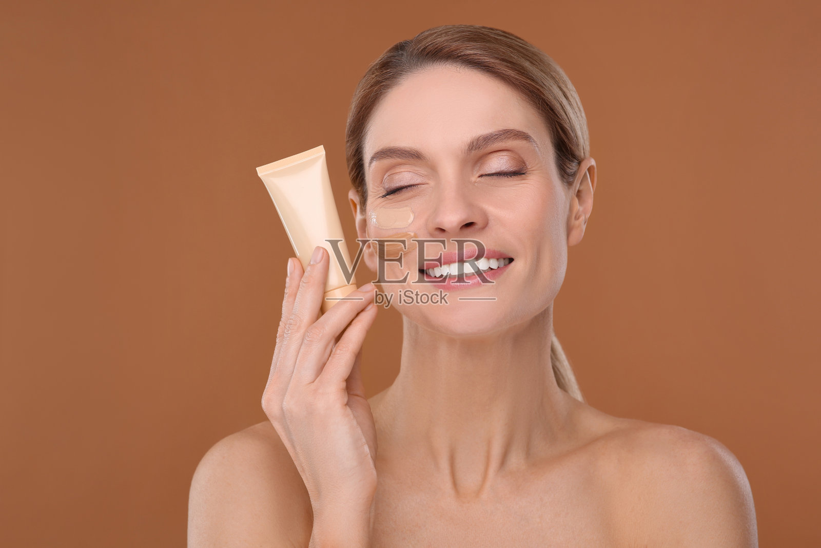 女士拿着粉底筒，棕色背景照片摄影图片