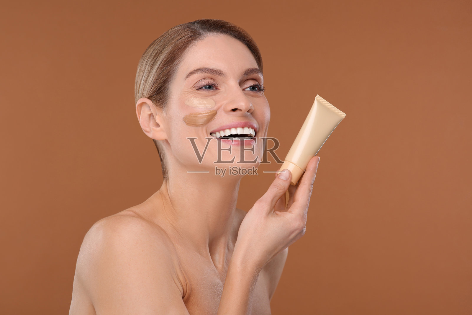 女士拿着粉底筒，棕色背景。文本空间照片摄影图片