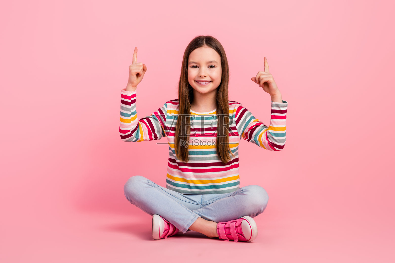 全身图像坐在地板上小女孩食指在头顶上的模型广告商店游乐园孤立的粉红色背景照片摄影图片